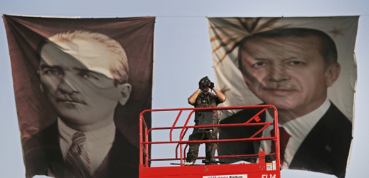 Hlídkující policista. Za ním jsou na plakátech snímky prezidentů - Mustafa Kemal Atatürk (vlevo), první prezident Turecka, a Recep Tayyip Erdoğan, ten současný.