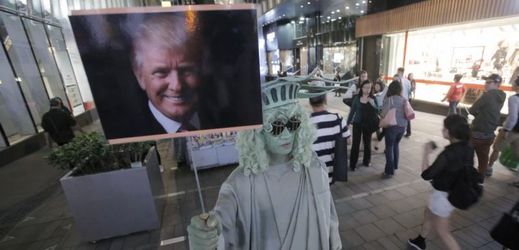 Pouliční umělec oblečený jako socha Svobody drží obraz Donalda Trumpa, Hongkong.