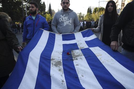 Řečtí studenti nesou státní vlajku potřísněnou krví z potlačené vzpoury roku 1973.