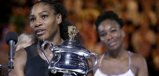 Serena Williamsová s pohárem, za ní její poražená sestra Venus.