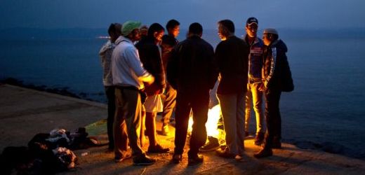 Uprchlíci semknutí kolem ohně. 