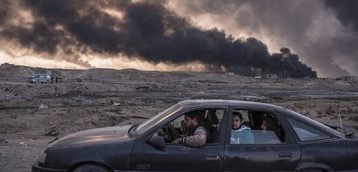 Muž se svou rodinou odjíždí z Mosulu. V dálce hoří ropná pole. Snímek je z listopadu 2016.