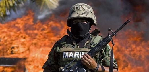 Mexický voják, za nímž hoří zabavené drogy.