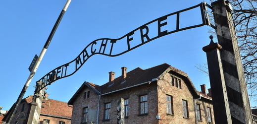 Brána koncentračního tábora v Osvětimi s nápisem Arbeit macht frei.