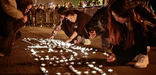 Demonstranti z čínské komunity skládají v pařížské ulici svíčky do nápisu violence (v překladu znamenajícího násilí).