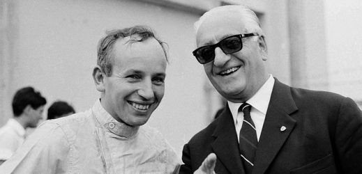 Zakladatel slavné automobilky Enzo Ferrari. Vlevo je britský závodník F1 John Surtees. Snímek je z roku 1964.