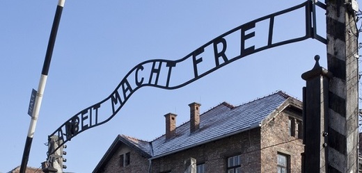 Brána koncentračního tábora v Osvětimi s nápisem Arbeit macht frei.