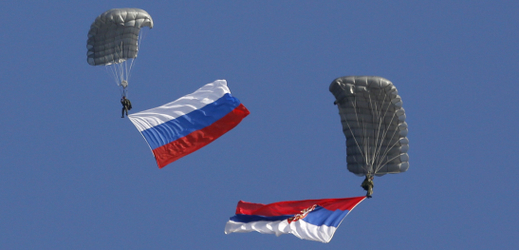 Parašutisté seskakují při rusko-srbském vojenském protiteroristickém cvičení s ruskou a srbskou vlajkou.