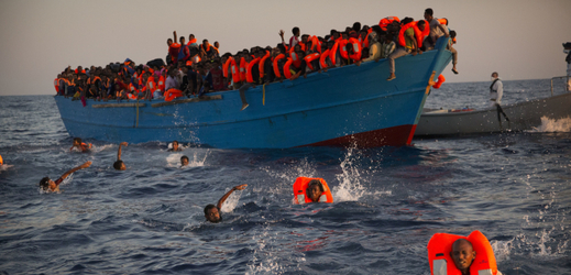Migranti skáčou z přeplněného dřevěného člunu během záchranné operace na Středozemním moři, asi 13 kilometrů severně od Sabrathy v Libyi (ilustrační foto).