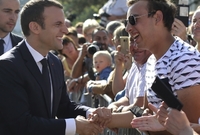 Prezident Emmanuel Macron si potřásá rukou s voličem.