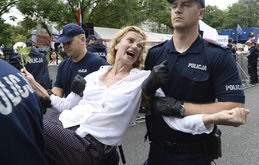 Policie odnášející jednu z protestujících žen.
