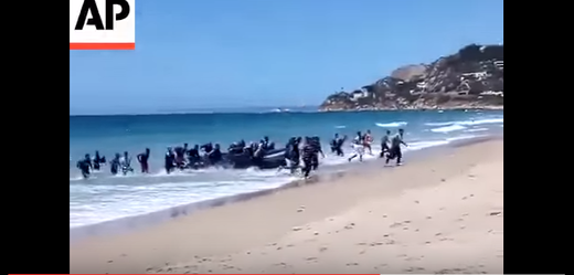 Uprchlíci na španělském pobřeží za bílého dne.