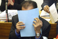 Hámid bin Abdal Sání si u soudu zakrývá tvář.