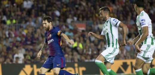 Barcelonský Messi utíká hráčům Betisu Real při vzájemném zápase 1. kola španělské ligy. 