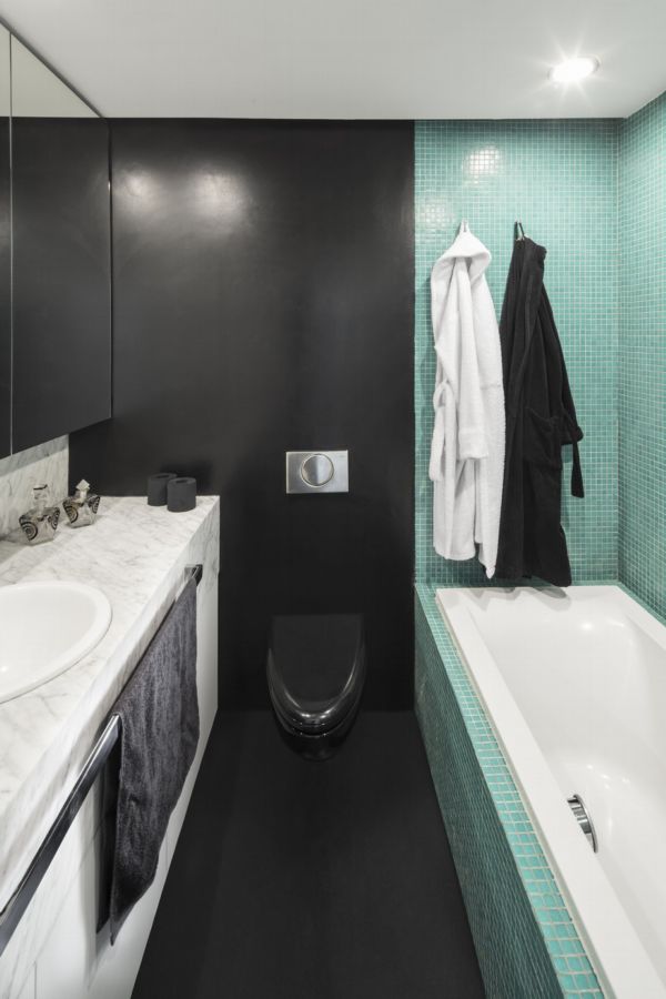 Šedá barva v koupelně je rozjasněna bílým nábytkem a zelenkavou mozaikou.