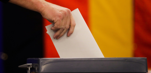 Volič vhazuje lístek do urny. Volební místnost v Berlíně.