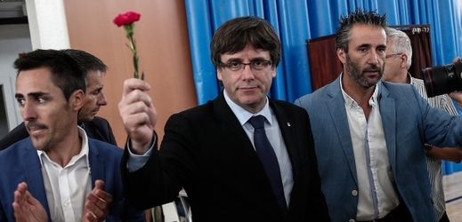 Katalánský premiér Carles Puigdemont (s květinou) v jedné z hlasovacích místností.