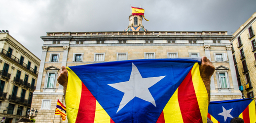 Muž s vlajkou Katalánska demonstruje za jeho nezávislost před palácem generála Catalunya.