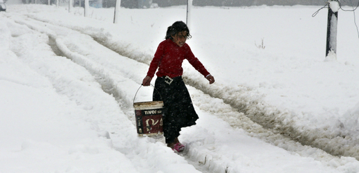 Syrská dívka jde po zasněžené cestě do uprchlického tábora (ilustrační foto).