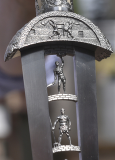 Ocelovou čepel dýky zdobí do detailu propracované postavy gladiátorů s různými zbraněmi.