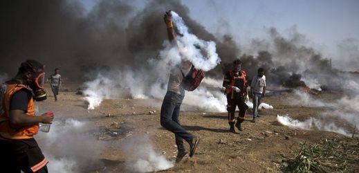 Protestující Palestinci házející slzný plyn na hranicích Pásma Gazy a Izraele.