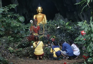 Lidé se u vchodu do jeskyně modlí za úspěšnou záchranu dětí.