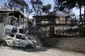 Po požáru se z ulic stala spálená země, na obrázku vrak auta a zničené domy. (FOTO: Thanassis Stavrakis).
