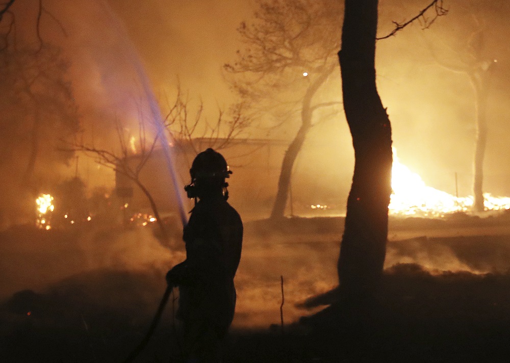 Hasič bojuje s plameny ve městě Mati, východně od Athén. (FOTO: Thanassis Stavrakis.)