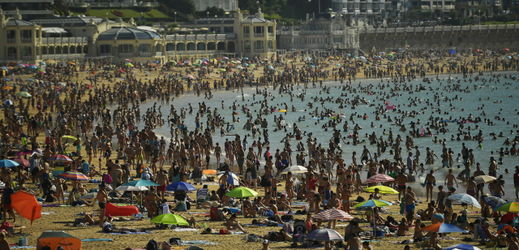 Přeplněné pláže ve Španělsku, lidé se chladí v moři.