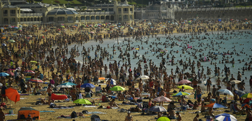 Přeplněné pláže ve Španělsku, lidé se chladí v moři.