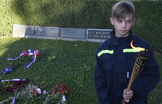 Dobrovolný hasič na čestné stráži u hrobu rodiny Masaryků.