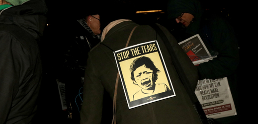 "Zastavte slzy": muž s tímto nápisem na bundě protestoval proti přístupu vlády k ochraně práv dětí migrantů.