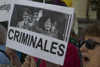 Snímek protestující ženy, která drží transparent s nápisem zločinci.