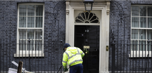 Pracovník uklízí před Downing Street. 