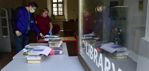 Pracovníci knihovny olomoucké Univerzity Palackého 15. dubna 2020 u výdejního okénka chystají objednané knihy. 