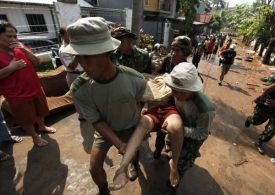 Záchranáři odnášejí jednu z obětí protržení hráze.