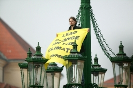 Muž vylezl na sloup lampy a rozvinul transparent Greenpeace.