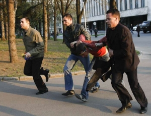 Ruští policisté v civilu odvádějí výtržníka od vladních budov.