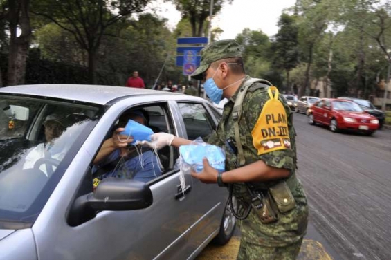 Policista v Mexico City rozdává roušky.