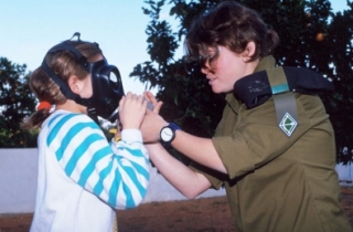 Vojačka učí dívku nasazování plynové masky. Izrael 1991, irácká válka.