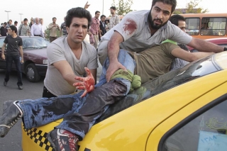 Zraněný muž ošetřovaný provizorně na kapotě taxíku v Teheránu.