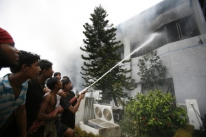Požárníci a dobrovolníci hasí oheň založený dělníky z továrny.
