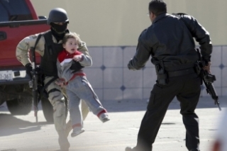 Jeden z vojáků odnáší dítě z místa střetu s gangy v Tijuaně.