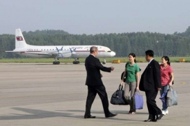 Novinářky míří k letadlu na letišti v Severní Koreji.
