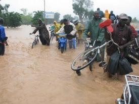 Lidé se brodí vodou ulicemi Ouagadougou.