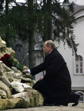 Putin, bývalý důstojník KGB, pokládá u pamětního kříže květiny.