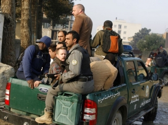 Afghánští policisté odvážejí do bezpečí cizince. Ti neskrývají strach.