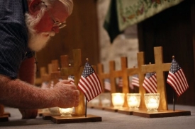 Muž zapaluje svíčky na památku obětí ve Fort Hoodu.