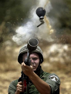 Izraelský voják zasahuje proti demonstrantům u hraniční zdi.