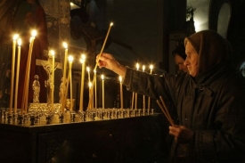 Žena zapaluje svíčku za oběti tragického požáru v Permu.